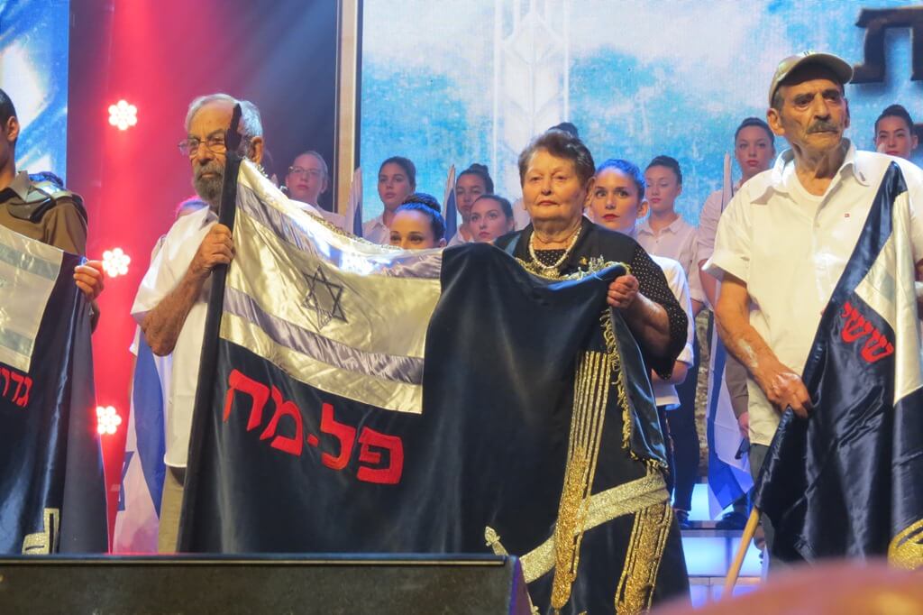 תמונה דגל הפלמ"ח מוצג לראווה בידי טובה עופר ופוצ'ו (אריה ויסלר). מימינם פסח עזריהו