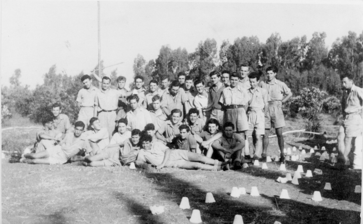 פלוגה ו', תיאור התמונה: האם שמעת על הפלמ"ח - מחלקת הירושלמים בעין החורש, המחלקה בפיקוד לוליק במסדר בוקר, מופיעים בתמונה: יעקב (ג'ורדן) כהן, בני בוגוסלבסקי, נחום רונן, בן ציון מימון, אבינעם, אליהו הרשקוביץ, מיקי האפט, מימין: דב צסיס, מכבי זלצברגר. תאריך צילום: 1942, נתקבל מ: בן ציון מימון: צרעה תמונה